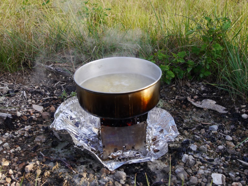 gamelle d'eau qui boue posé sur un réchaud à bois.